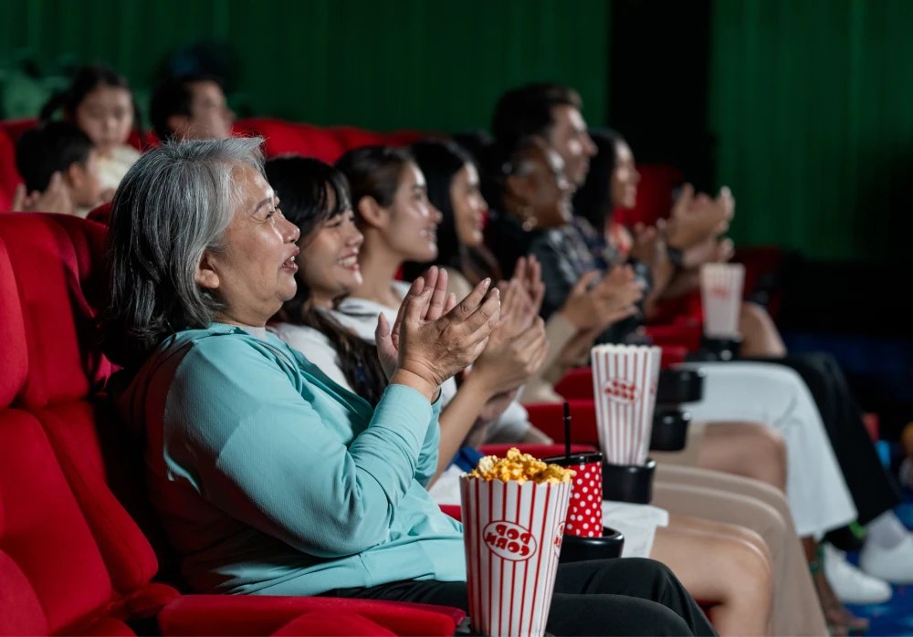 People enjoying movie experience at a multiplex in Greater Noida with red recliner seats, popcorn, and entertainment ambience.
